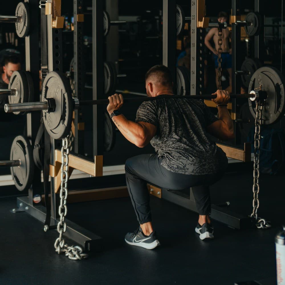 Male athlete performing barbell back squat in power rack